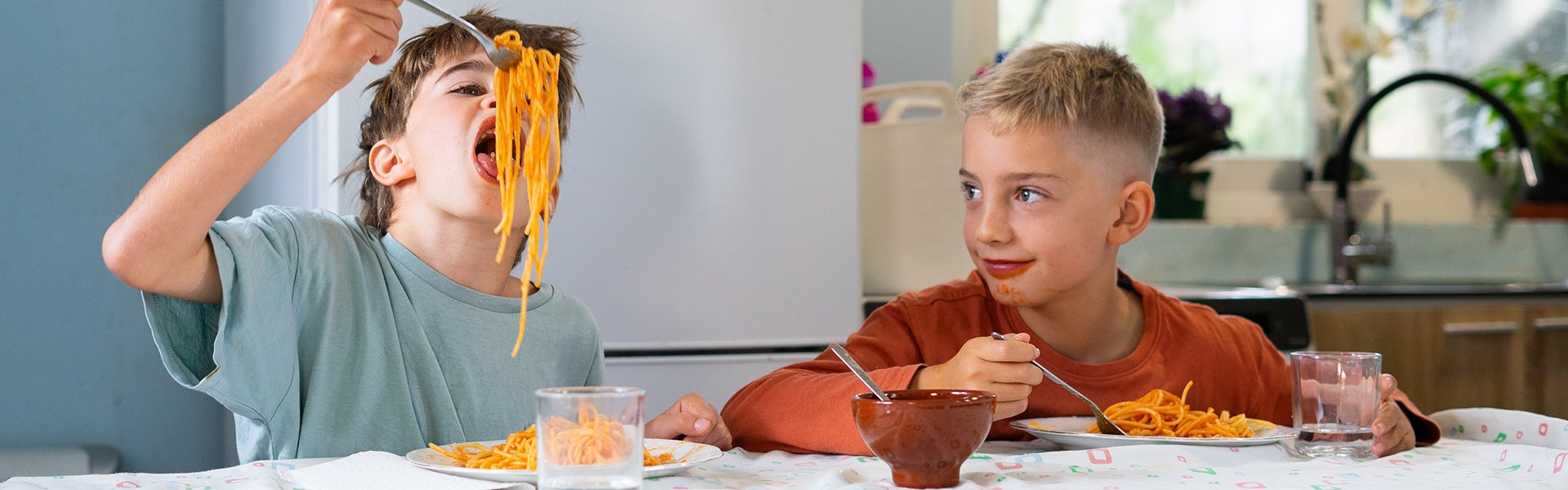 Kids eating pasta with sauce
